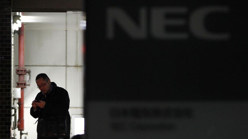En mann rusler forbi hovedkvarteret til NEC i Tokyo. Selskapet kunngjorde torsdag at de må si opp 10.000 ansatte.